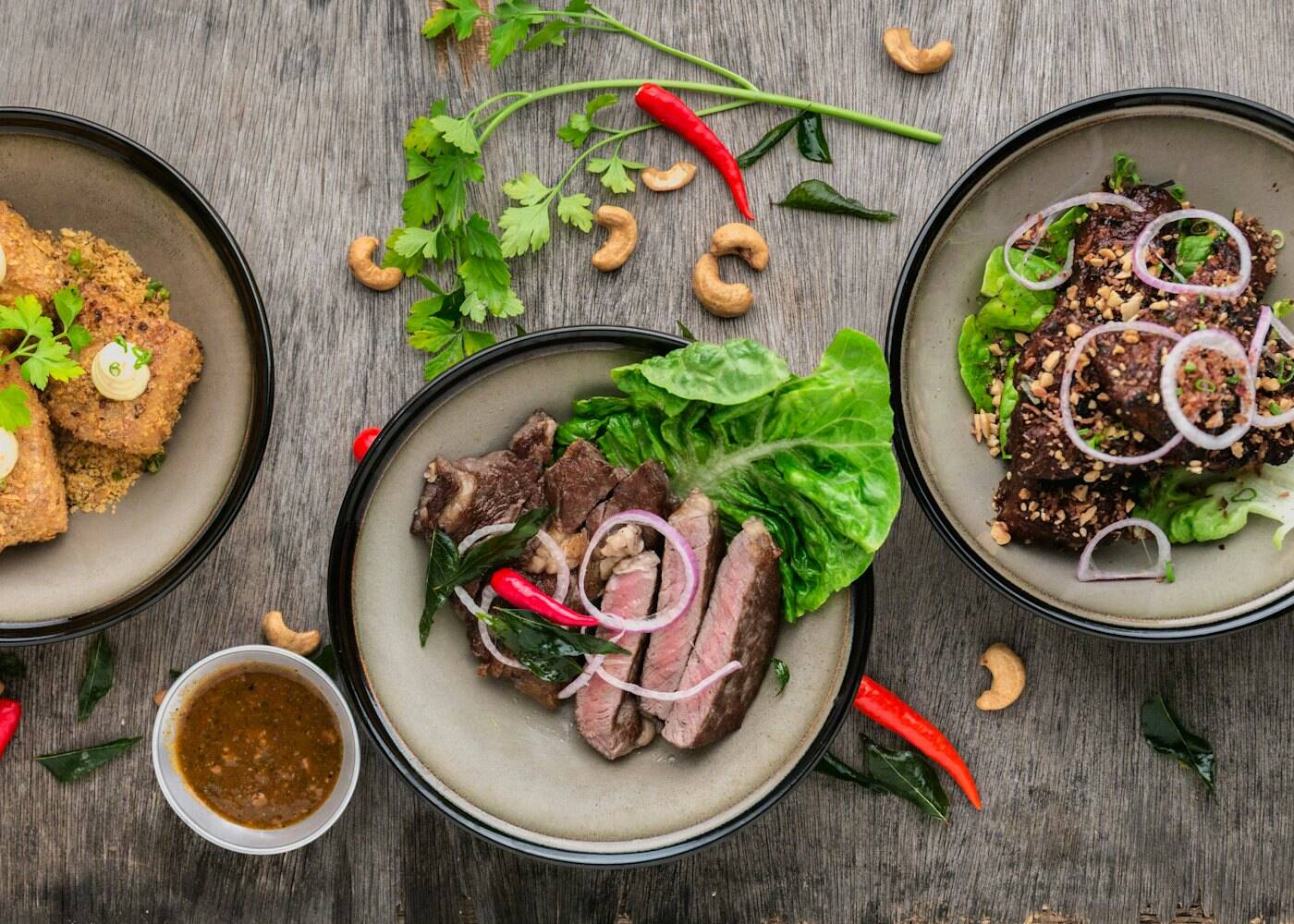 A table of plated dishes with fresh herbs and chillies