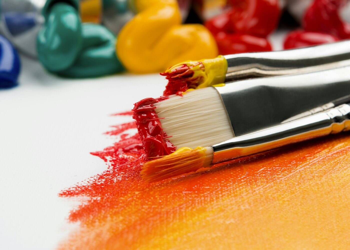 A paintbrush laying down bright orange paint